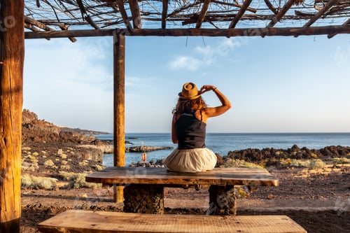 Preview: Tourist woman with her back turned at sunset on the beach of Tacoron on El Hierro, Canary Islands