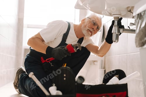 Preview: Senior plumber repairing sink pipe using adjustable wrench