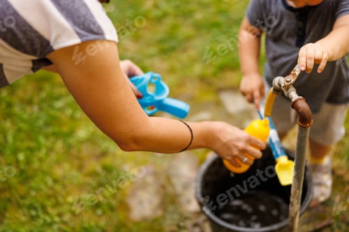 Preview: Mother and son filling toy gun with water while playing in the backyard of their home