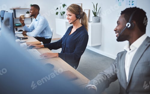 Preview: Happy young caucasian call centre telemarketing agent talking on a headset while working on compute