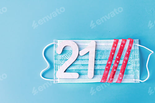 Preview: Number 21 and festive ribbon on a medical protective mask on a blue background