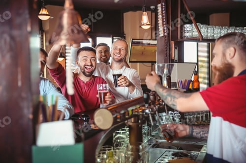 Preview: Friends drinking beer at counter in bar