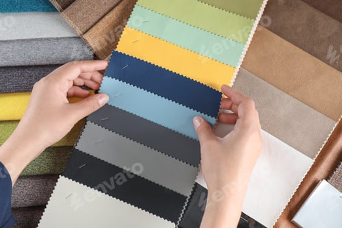 Preview: Young woman choosing among upholstery fabric samples, closeup. Interior design