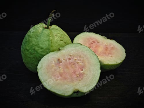 Preview: a slice of guava fruit sitting next to another sliced up piece