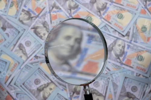 Preview: Blurred image of us dollar bill through magnifying lens checking banknotes