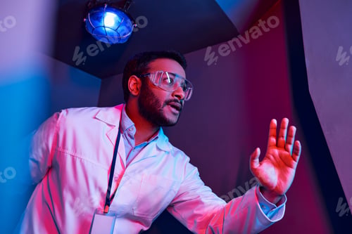 Preview: future exploration, worried indian scientist looking away in neon light in innovation hub