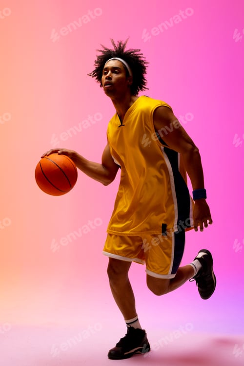 Preview: Image of biracial basketball player bouncing basketball on pink to orange background