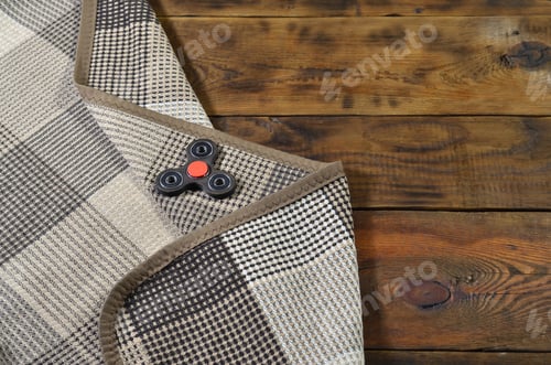 Preview: A rare wooden handmade spinner lies on a checkered plaid on a brown wooden background