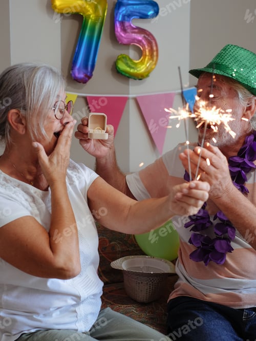 Preview: Cheerful Caucasian senior couple celebrating 75th birthday with sparkles