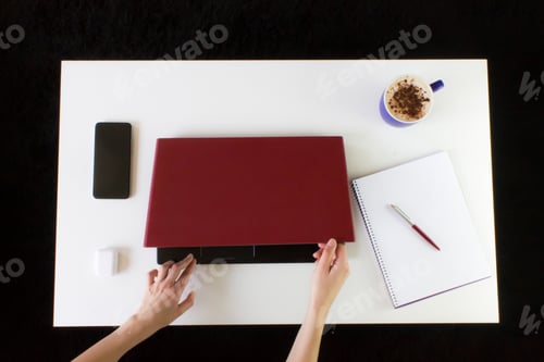 Preview: High angle shot of a person working at a work desk with a laptop, a cup of coffee, and mobile phone
