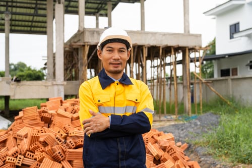 Preview: A male architect in a hard hat and safety vest reviews construction documents construction