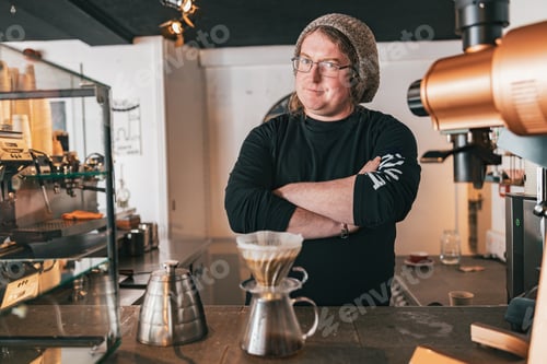 Preview: Men barista making a drip filter coffee standing by counter in coffeeshop and looking camera
