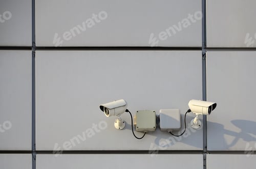 Preview: White surveillance camera built into the metal wall of the office building