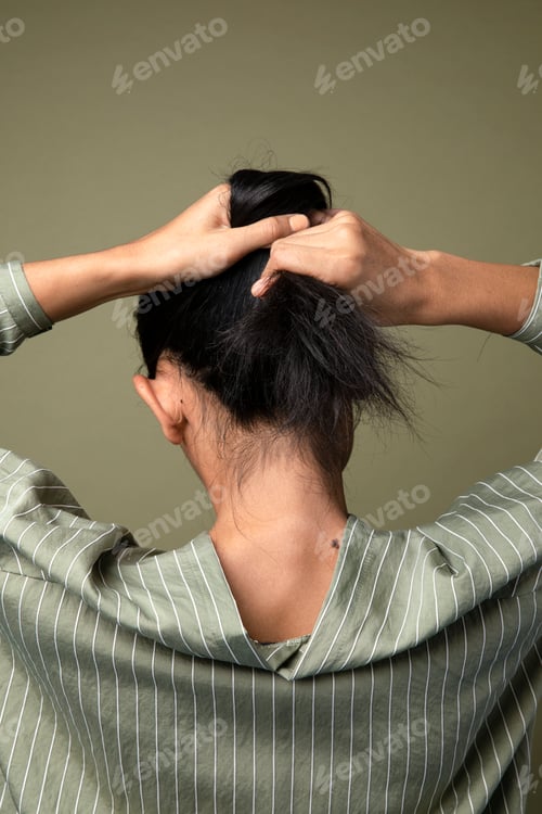 Preview: Rear view of a woman putting her long hair up