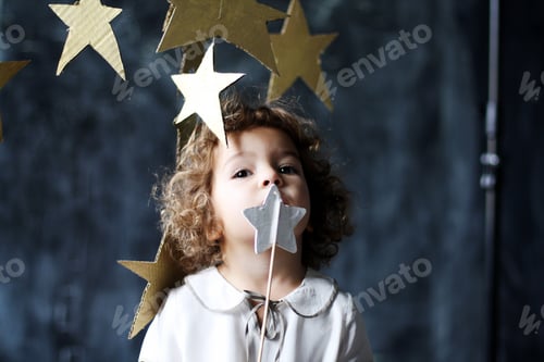 Preview: Studio portrait of cute curly parisian girl with handmade star in hands on dark background.