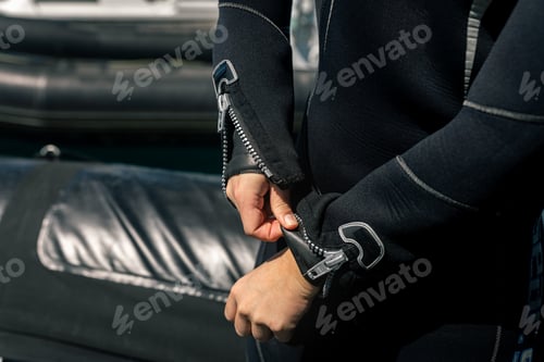 Preview: Diver zipping up diving suit on boat before scuba diving