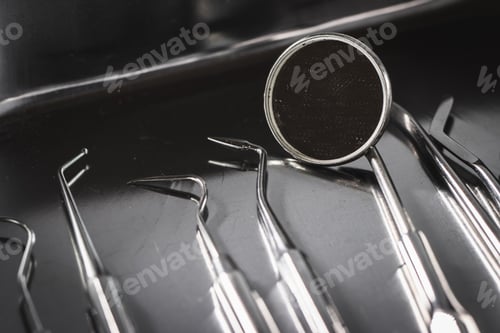Preview: Closeup of surgical tools on a black tray under the lights against a blurry background