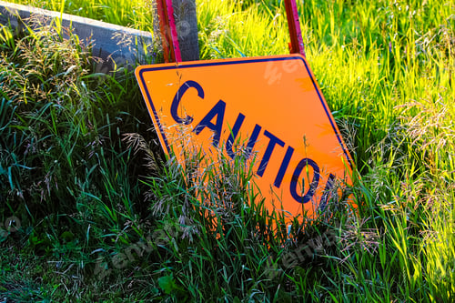 Preview: A caution construction sign laying in the grass