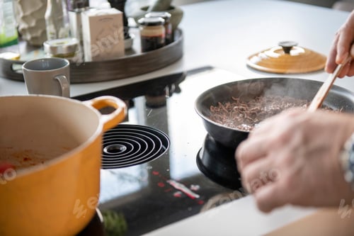 Preview: Adult man preparing mince for a lasagne in his modern kitchen