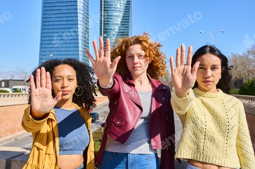 Preview: Three young women showing stop sign with hands in the city
