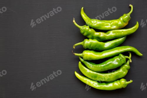 Preview: Top view, green chili peppers on black surface. Flat lay, from above, overhead. Copy space.