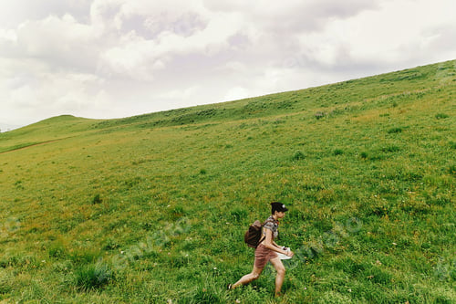 Preview: Stylish hipster woman traveler walking on hill of summer mountains
