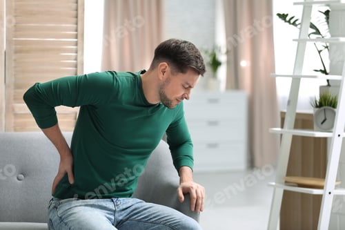 Preview: Young man suffering from back pain at home