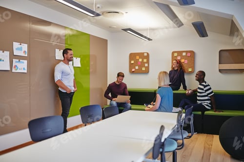 Preview: Smiling group of designers talking together in a modern office