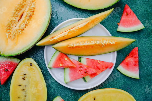 Preview: Fresh melon and watermelon slices arranged on a dark green textured surface
