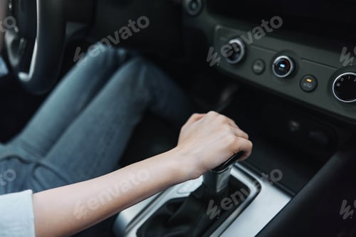 Preview: Woman's hands gripping the steering wheel of a car with the gear stick prominently in the center