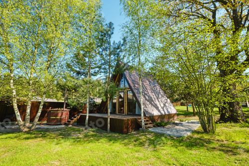 Preview: Cozy A-frame cabin nestled among trees in a serene landscape during bright daylight