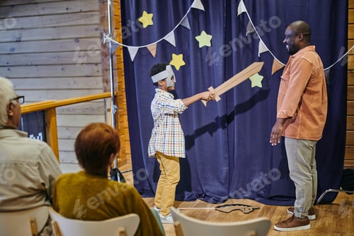 Preview: Happy boy in costume of knight holding sword against his father