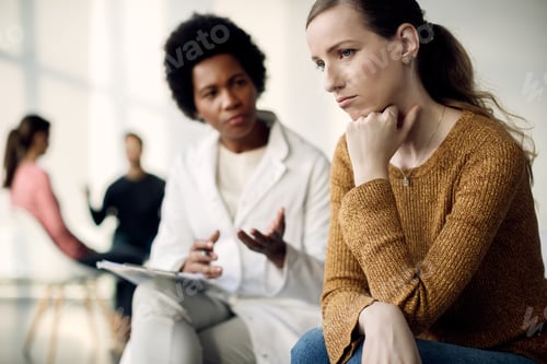 Preview: Young sad woman having a meeting with psychotherapist at medical center.