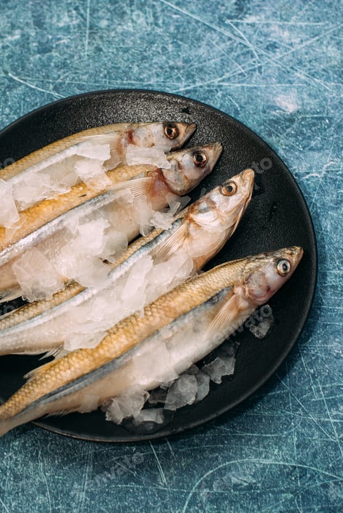 Preview: Fresh fish in ice on a blue background. Close up.
