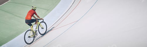 Preview: Top view of man in sports clothing cycling on track outdoors