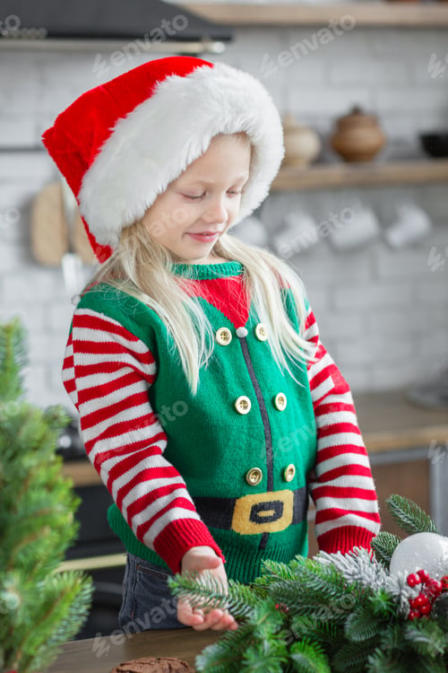 Preview: Girl in santa claus hat smiling and posing in cozy kitchen