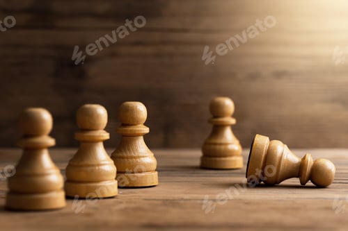 Preview: Wooden chessmen standing with one chess pawn lying.
