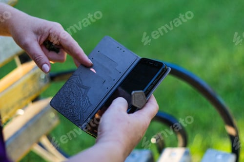 Preview: close-up female hands touching on the phone outside, outdoor.