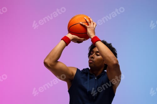 Preview: Image of biracial basketball player throwing basketball on pink to blue background