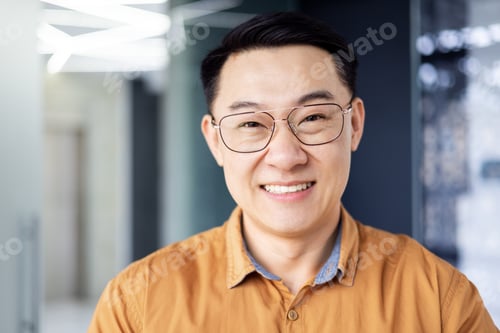 Preview: Close up photo portrait of successful young Asian investor, man in glasses smiling and looking at