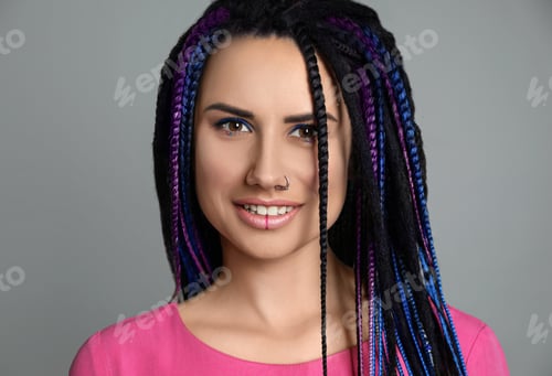 Preview: Beautiful young woman with nose piercing and dreadlocks on grey background
