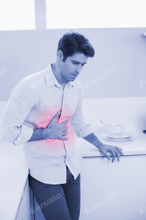 Preview: Casual Young Man With Stomach Pain Standing In The Kitchen At Home