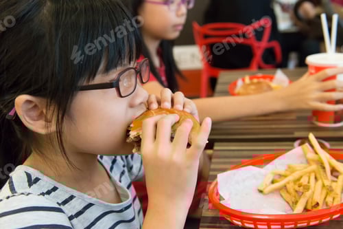 Preview: Happy Young Person Enjoys Eating a Burger Indoors