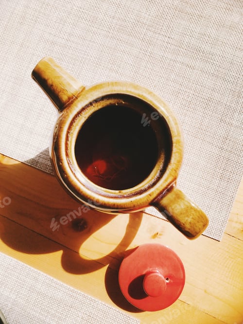Preview: ceramic teapot with hot tea on the table
