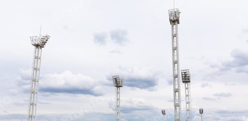 Preview: Panoram view of six light towers on gray sky backdrop at stadium.