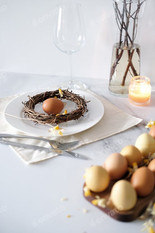 Preview: Easter table setting with candles, willow branches and yellow eggs in the nest