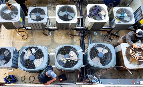 Preview: Overhead of utility workers maintaining outside air conditioning HVAC units at a beach condo.
