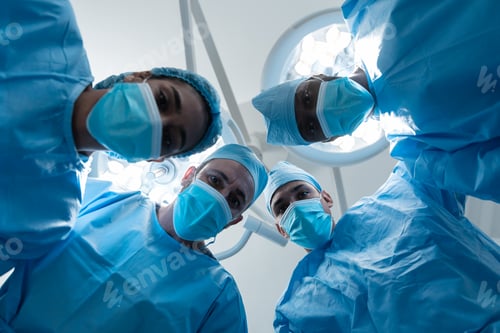 Preview: Diverse surgeons wearing face masks and protective clothing in operating theatre