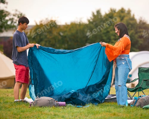 Preview: Young Couple Putting Up Tent At Summer Music Festival Unpacking Camping Equipment