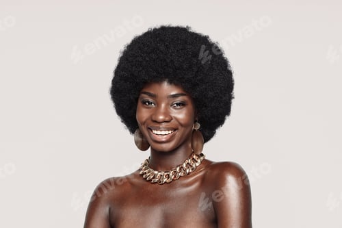 Preview: Portrait of beautiful young African woman in golden jewelry looking at camera and smiling